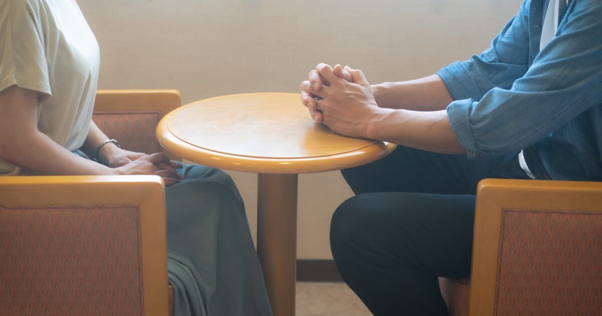 テーブル越しに向かい合い話し合うカップルの真剣な会話シーン