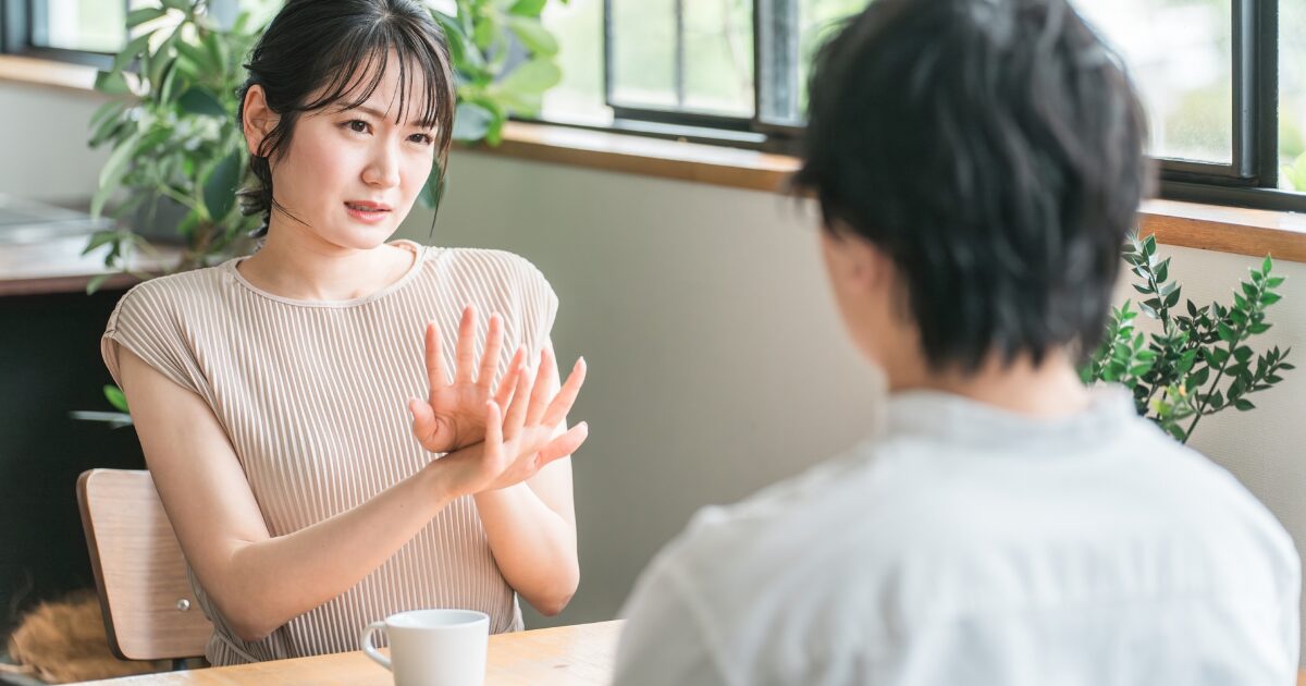 カフェで向かい合い手振りで説明する女性と話を聞く男性