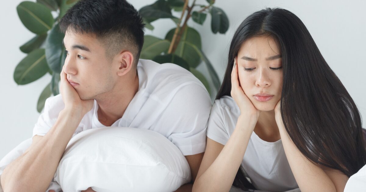 ベッドで背を向け合い悩むカップルの関係悪化イメージ