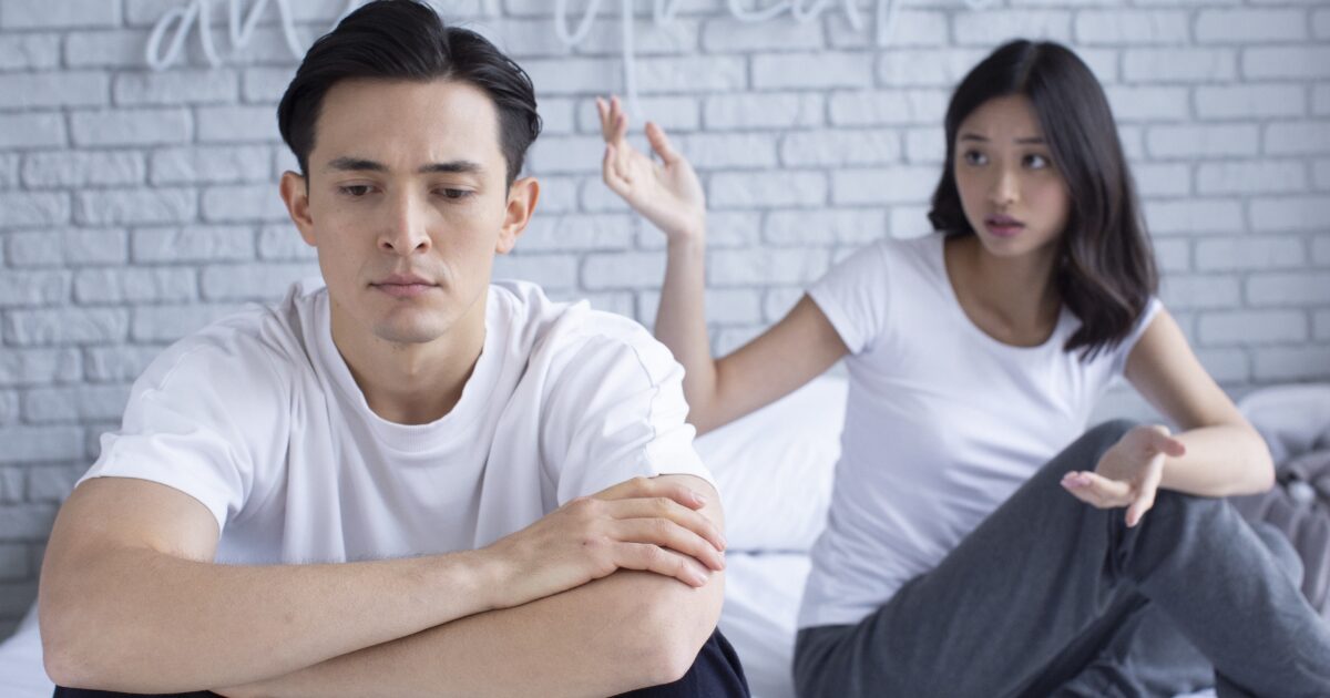 ベッドで腕を組み無言の男性と話しかける女性のすれ違い