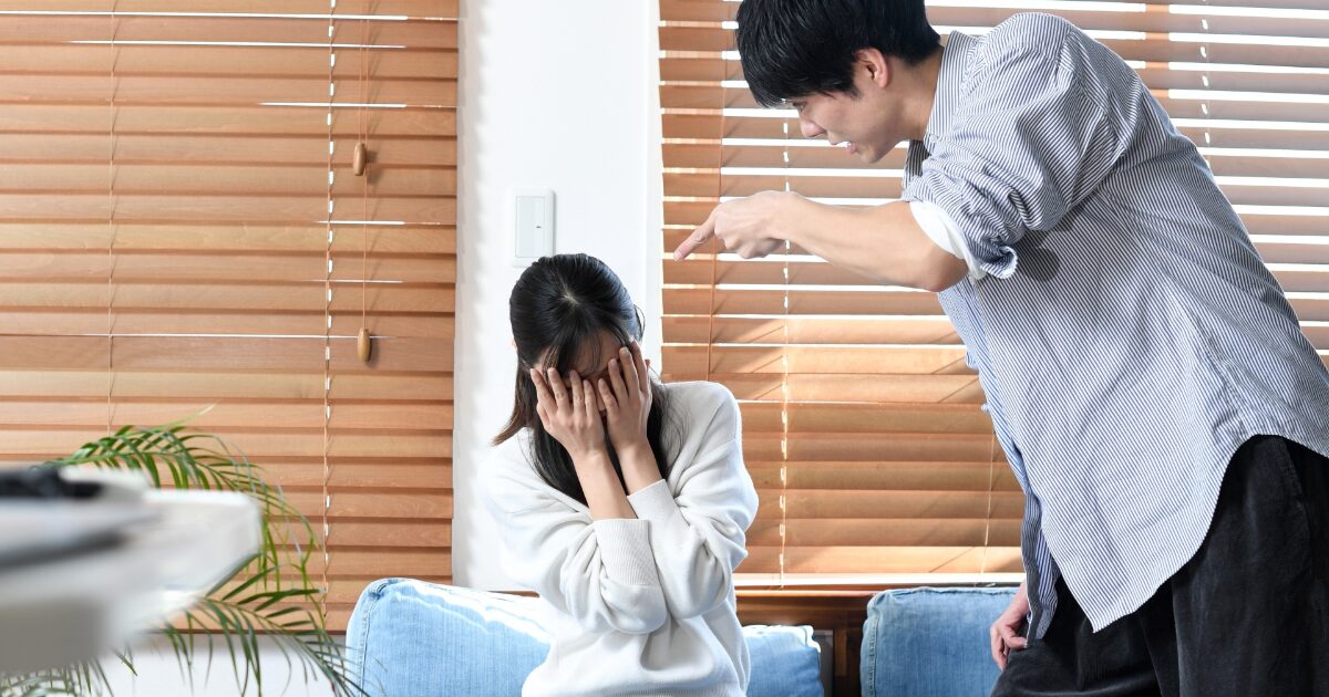 男性が指差して叱責し女性が顔を覆う家庭内トラブルのイメージ