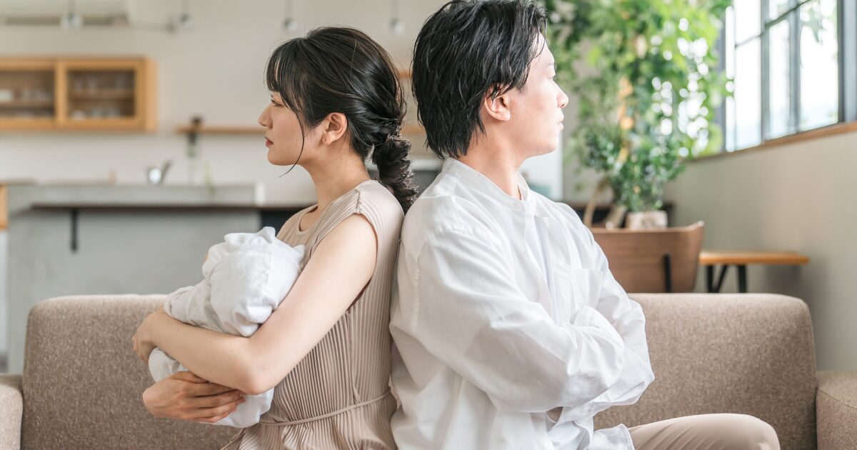 ソファで背中合わせに座る夫婦の冷え切った関係イメージ