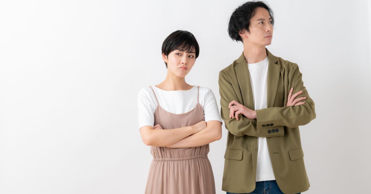 腕を組み不満そうにそっぽを向く男女の対立イメージ