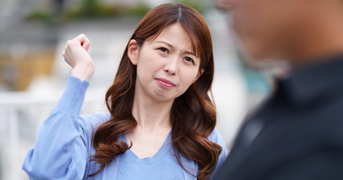 怒りの表情で拳を振り上げる女性と対峙する人物の口論シーン