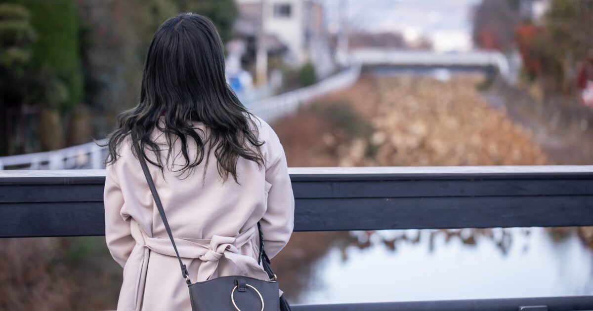 橋の上で後ろ姿の女性が一人佇む孤独なシーン