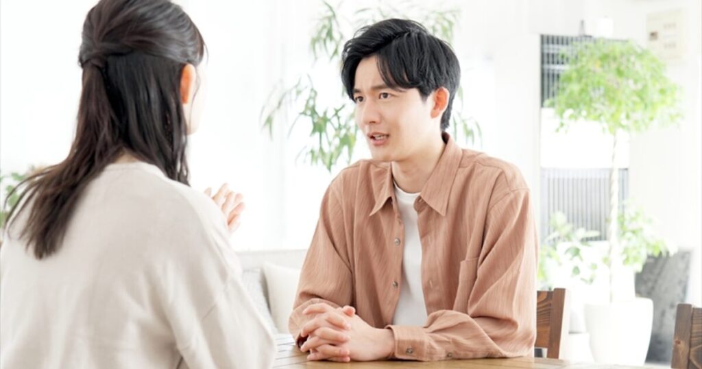 テーブルで向かい合い真剣に話し合うカップルの相談シーン