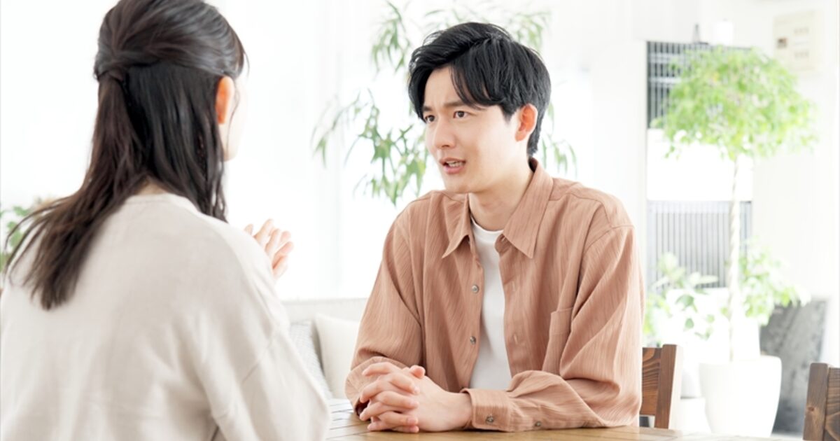 テーブルで向かい合い真剣に話し合うカップルの相談シーン